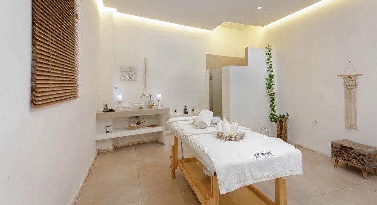 Warm-white private massage room with natural wood at The Moment in Athens